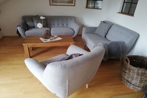 A living room with a grey sofa, a wooden coffee table, and a grey armchair. - Holiday apartment with 3 bedrooms (Wangerland)