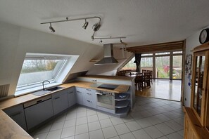 Een moderne keuken met dakraam, inbouwoven en een eethoek met uitzicht.