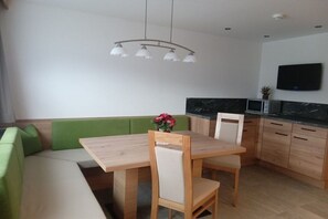A modern kitchen with a dining area, green seating, and a flat-screen TV. - Hippach Sporer family (Hippach)