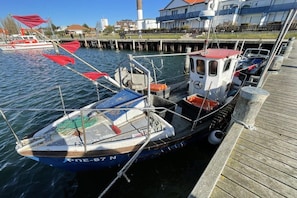 A small boat docked at a pier with a house in the background. - Holiday apartment with 1 bedroom (Timmendorf-Strand, Insel Poel)