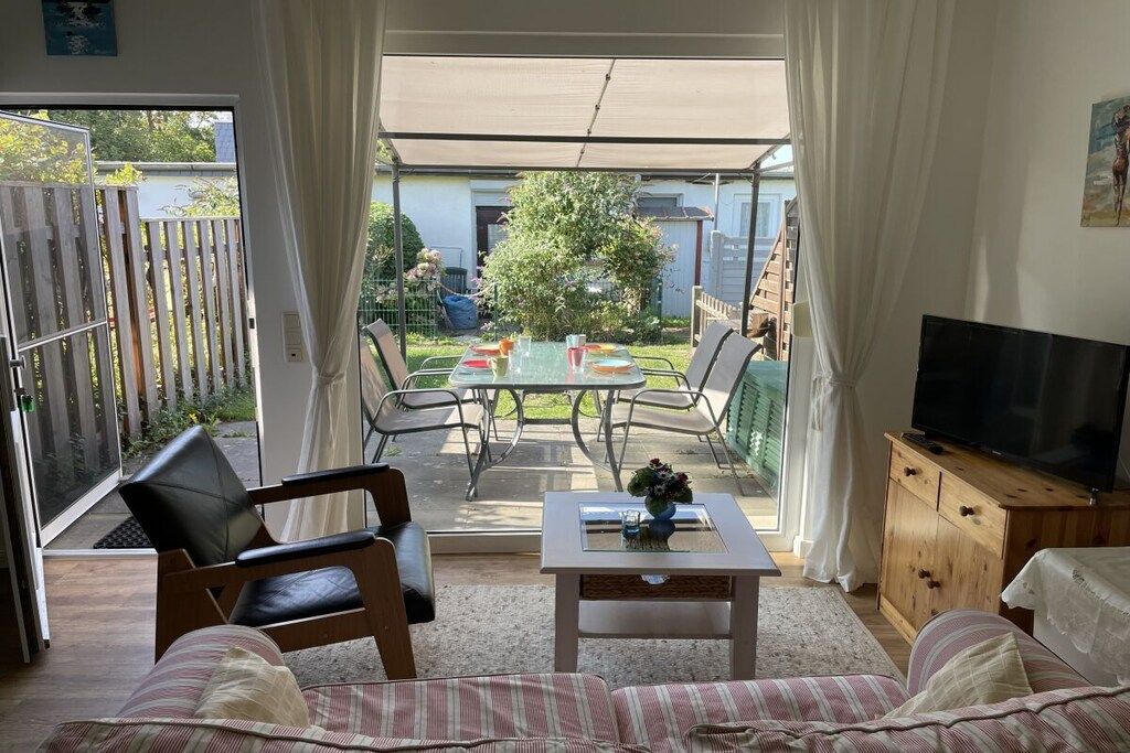 A living room with a sofa, a TV, a table with a vase, and a patio area with a table and chairs.