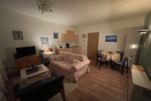 A compact living space with a television, sofa, dining table, and kitchenette. - Holiday apartment with 1 bedroom (Timmendorf-Strand, Insel Poel)