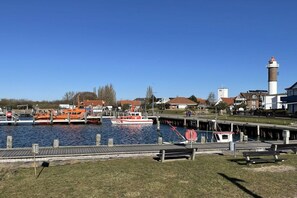 Un port esportiu amb vaixells amarrats, un far i un moll amb bancs.