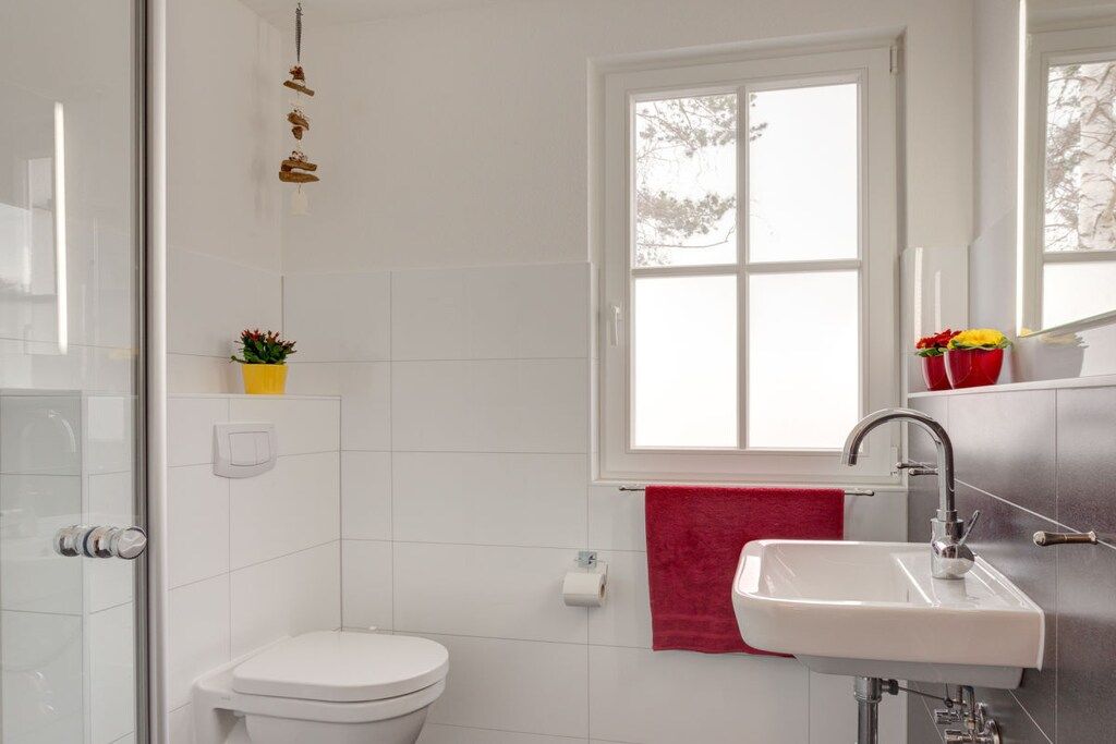 A modern bathroom with a toilet, sink, and a window.
