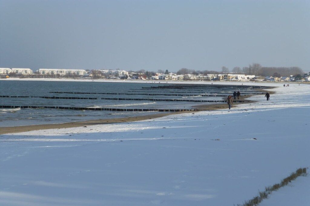 A beach with a clear view of the ocean and a distant shoreline with buildings.