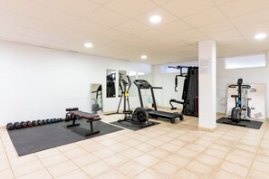 Ein Fitnessraum mit Cardiogeräten, Kurzhanteln und einer Bank.