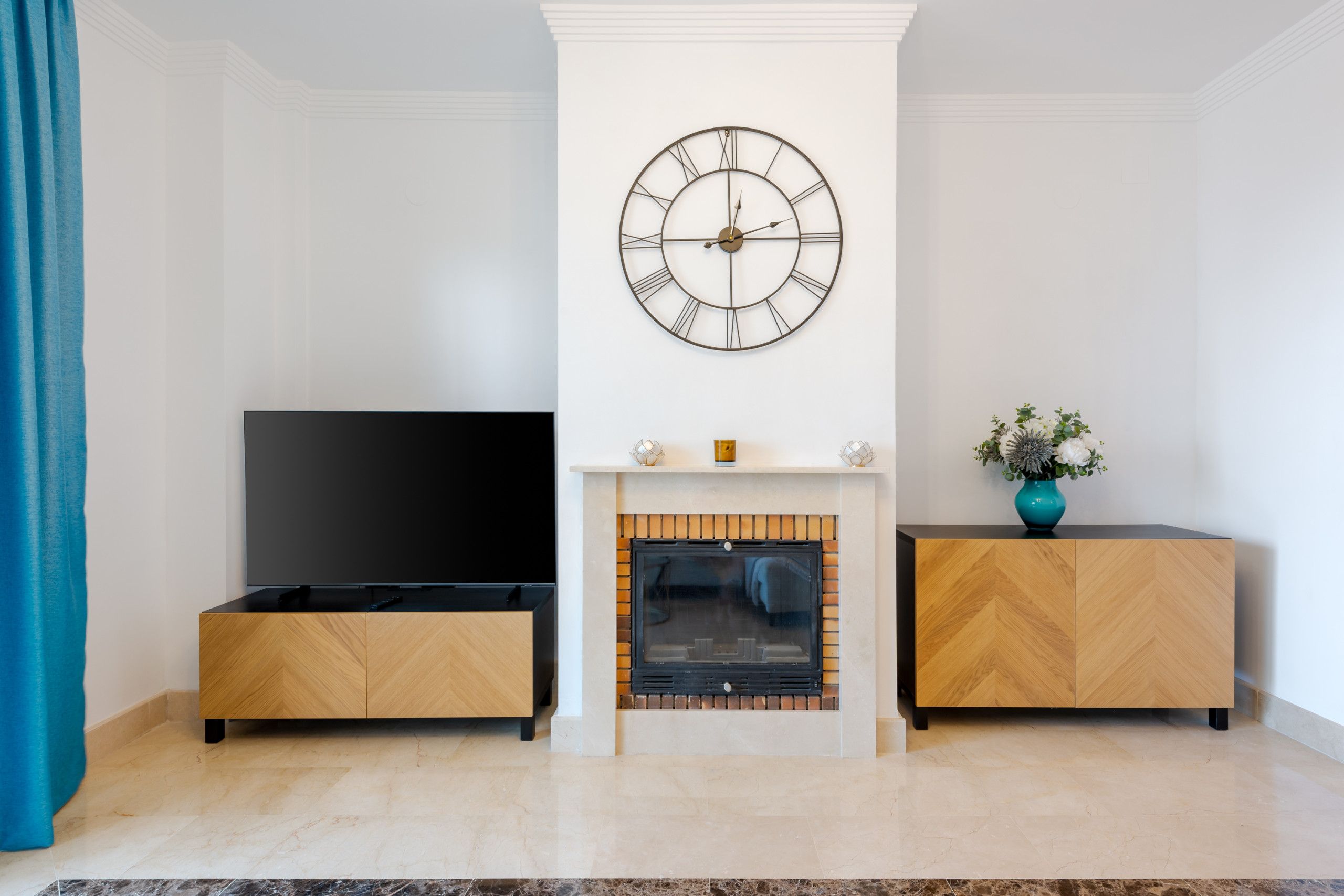 Una sala de estar con un televisor de pantalla plana, una chimenea y un reloj en la pared.