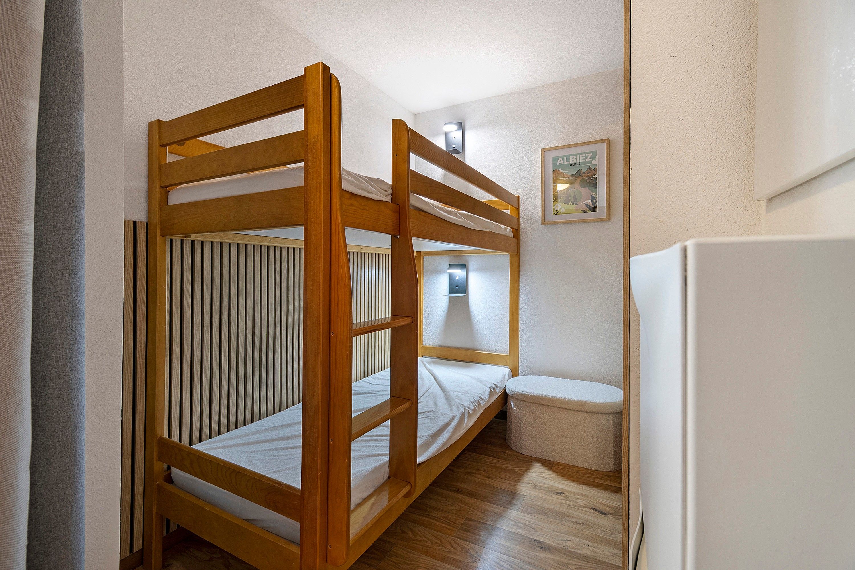 Ein Etagenbett mit Holzrahmen, ein kleiner Nachttisch, eine Wandleuchte und ein gerahmtes Bild an der Wand.