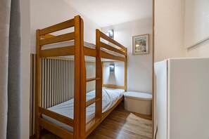 A bunk bed with a wooden frame, a small bedside table, a wall-mounted light, and a framed picture on the wall. - Apartment 'Albiez 4 to 6 guests' with mountain view and balcony (Albiez-Montrond)