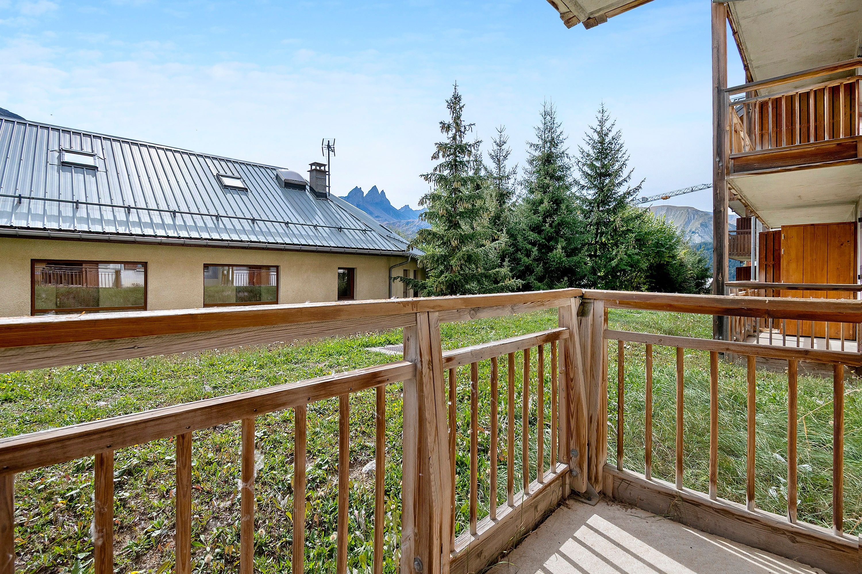 Ein Holzbalkon mit Blick auf einen Berg und ein Gebäude mit einer Metallbedachung.