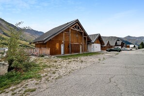 A wooden building with a sloped roof, a gravel driveway, and a mountainous backdrop. - Apartment 'Albiez 4 to 6 guests' with mountain view and balcony (Albiez-Montrond)