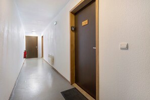 A hallway with a fire extinguisher, a door with a sign, and a light switch on the wall. - Apartment 'Albiez 4 to 6 guests' with mountain view and balcony (Albiez-Montrond)