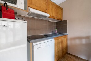 A compact kitchen with a white refrigerator, a dishwasher, and wooden cabinets. - Apartment 'Albiez 4 to 6 guests' with mountain view and balcony (Albiez-Montrond)