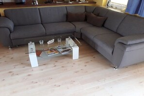 A grey sectional sofa with a glass coffee table in a living room. - Holiday apartment in Glowe with swimming pool (Glowe)