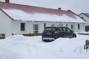 A car partially buried in snow in front of a house with a red roof. - Holiday apartment in Glowe with swimming pool (Glowe)