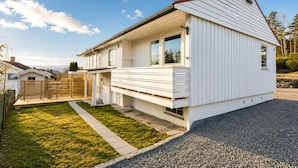 A white single-story house with a covered porch, a small front yard, and a gravel driveway. - Bright & Spacious Guest Suite Near Drammen (Drammen)