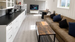 A modern kitchen with white cabinetry and a black countertop, a dining area with a round table, and a living room with a brown sofa and cushions. - Bright & Spacious Guest Suite Near Drammen (Drammen)