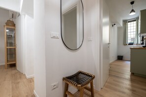 Ein Flur mit einer hölzernen Bank, einem Spiegel an der Wand und einer Küchenzeile mit Fenster.