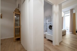 Eine moderne Wohnung mit einem Holzschrank, einer Waschmaschine und Blick ins Freie.
