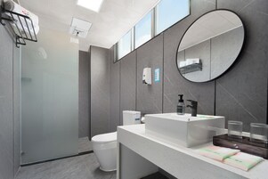 Un baño moderno con inodoro, lavamanos y espejo.