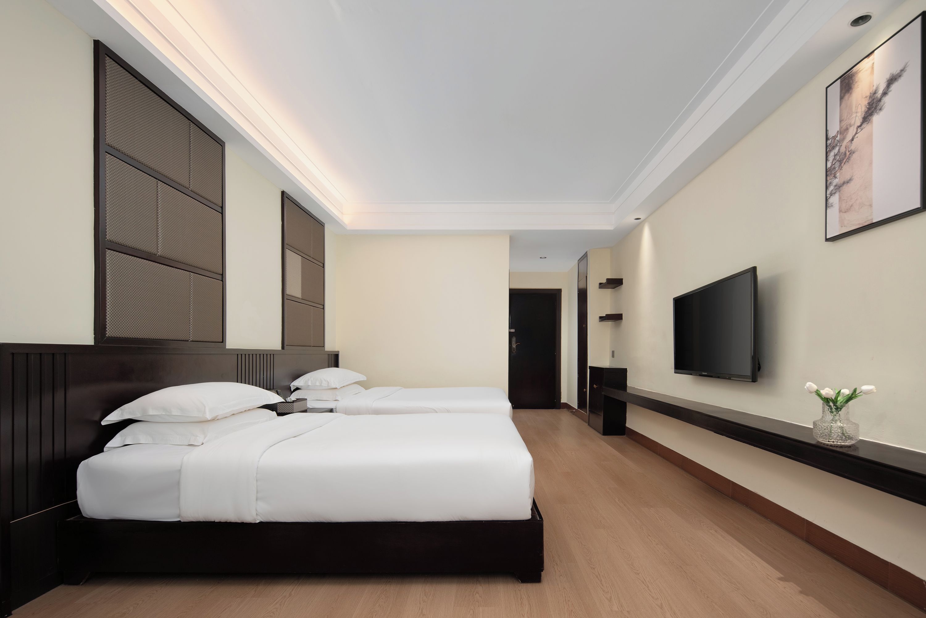 Habitación de hotel con dos camas, un televisor y una puerta que da a otra habitación.