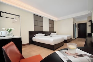 Una habitación de hotel con una cama, mesitas de noche, un escritorio y una silla.