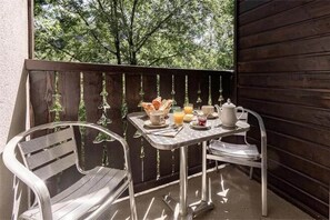 Ein Balkon mit einem Frühstückstisch, komplett mit Croissants, Saft und einem Teekessel.