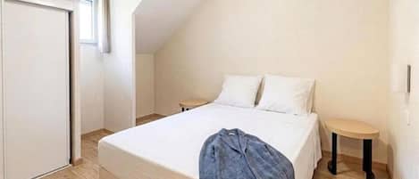 A bedroom with a bed, two bedside tables, a wardrobe, and a window.