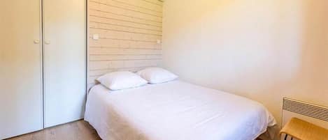 A bedroom with a bed, a wooden floor, and a radiator.