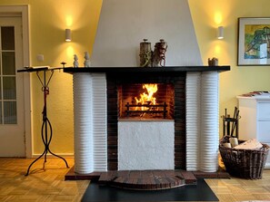 A fireplace with a fire, a white mantelpiece, and a black hearth rug. - Haus Schneekappe - 190qm beste Lage (Winterberg)