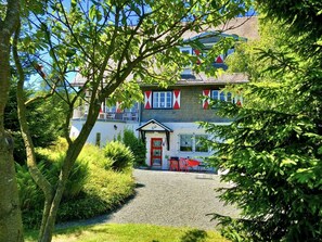 Ein Gebäude mit rotem Eingangsbereich, einem Balkon und einem Kiesweg, der zum Eingang führt.
