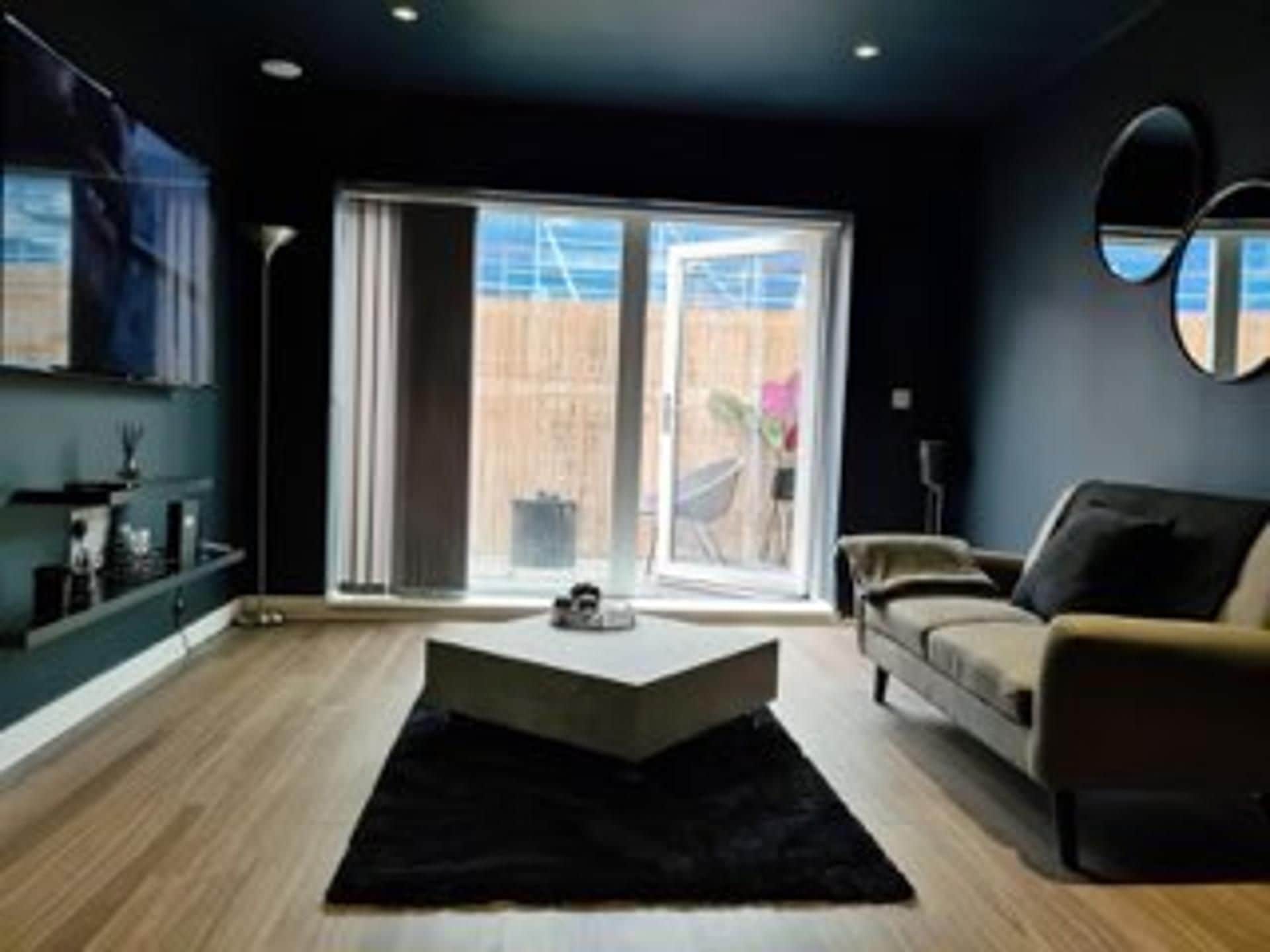 Ein modernes Wohnzimmer mit einer Couch, einem Couchtisch und einem großen Fenster.