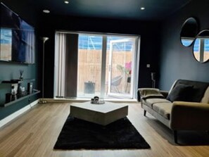 Ein modernes Wohnzimmer mit einer Couch, einem Couchtisch und einem großen Fenster.