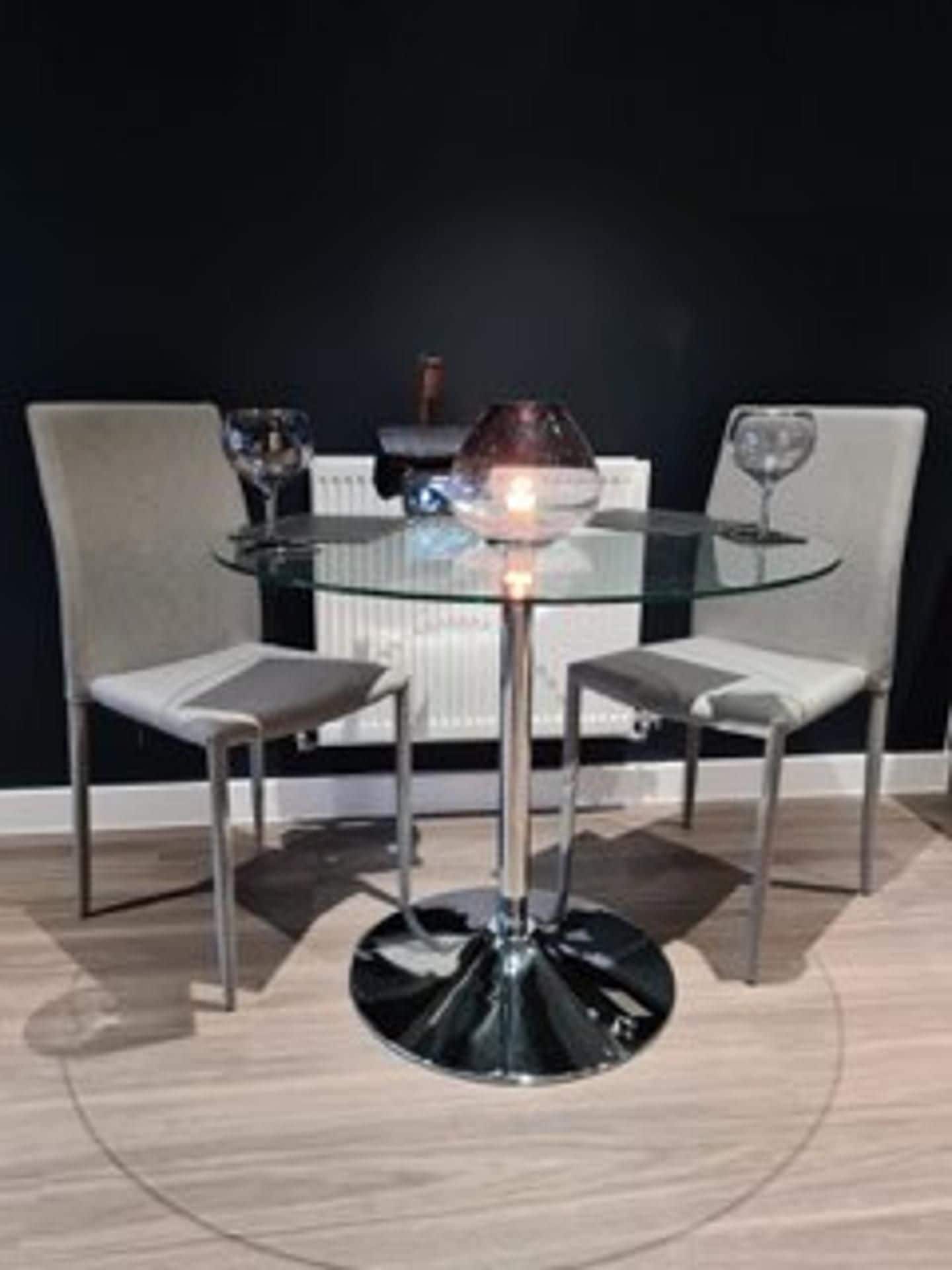A modern dining table with a glass top and metal base, surrounded by two chairs with cushioned seats.