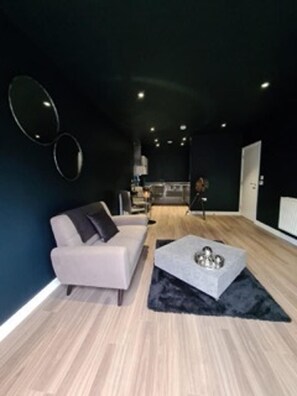 Ein modernes Wohnzimmer mit einer Couch, einem Couchtisch und einer Ringlampe an der Wand.