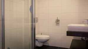 Un bagno con cabina doccia in vetro, un water bianco e un lavabo con piano d'appoggio scuro.