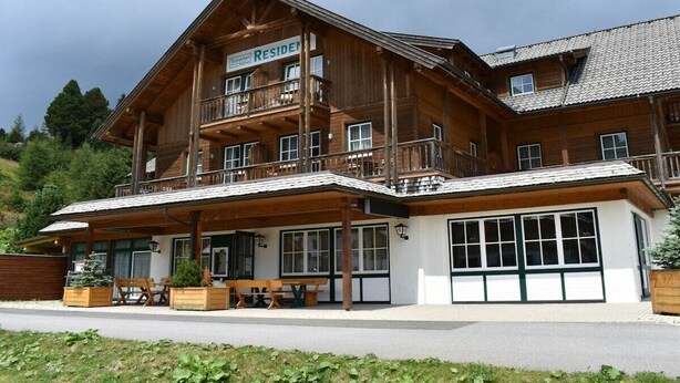 Un grande edificio in legno con un cartello che riporta la scritta 'RESIDEN'.