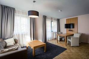 Ein modernes Wohnzimmer mit einer Couch, einem Couchtisch, einem Esstisch und einem an der Wand montierten Fernseher.
