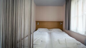 Una camera d'albergo con un letto, tende e una testiera.