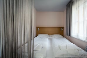 Ein Hotelzimmer mit Bett, Vorhängen und Kopfteil.