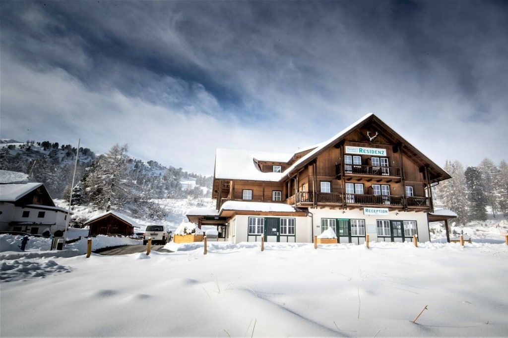 Un chalet en bois comprenant un espace d’accueil, de nombreuses fenêtres et une enseigne indiquant « RÉSIDENCE ».
