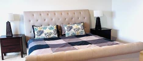 A bedroom with a large bed, two bedside tables, and a ceiling light.