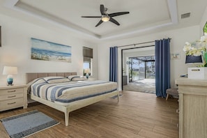 A bedroom with a bed, bedside tables, a ceiling fan, a window with curtains, and a view of the outdoors. - Villa in Cape Coral with swimming pool (Cape Coral)