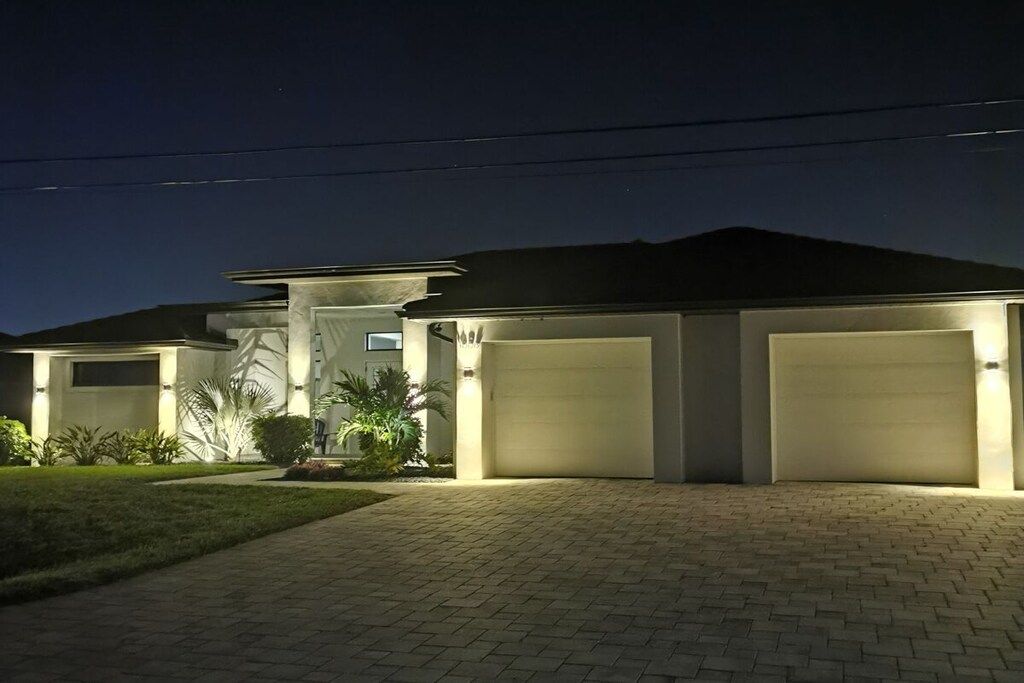 A modern house with a paved driveway and two garage doors.
