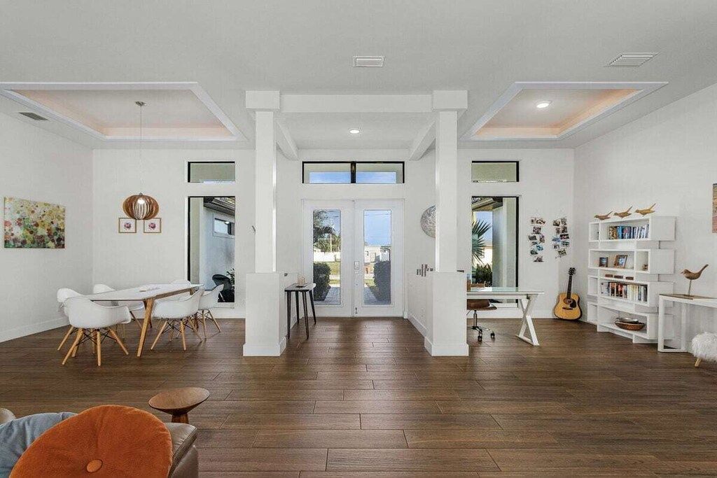 A spacious living area with a dining table, chairs, and a bookshelf.