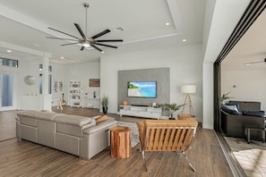 A modern living room with a sectional sofa, a wooden coffee table, and a television mounted on the wall. - Villa in Cape Coral with swimming pool (Cape Coral)