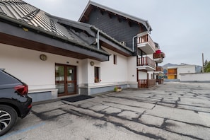 Een gebouw met een schuin dak, een houten balkon en een auto ervoor geparkeerd.