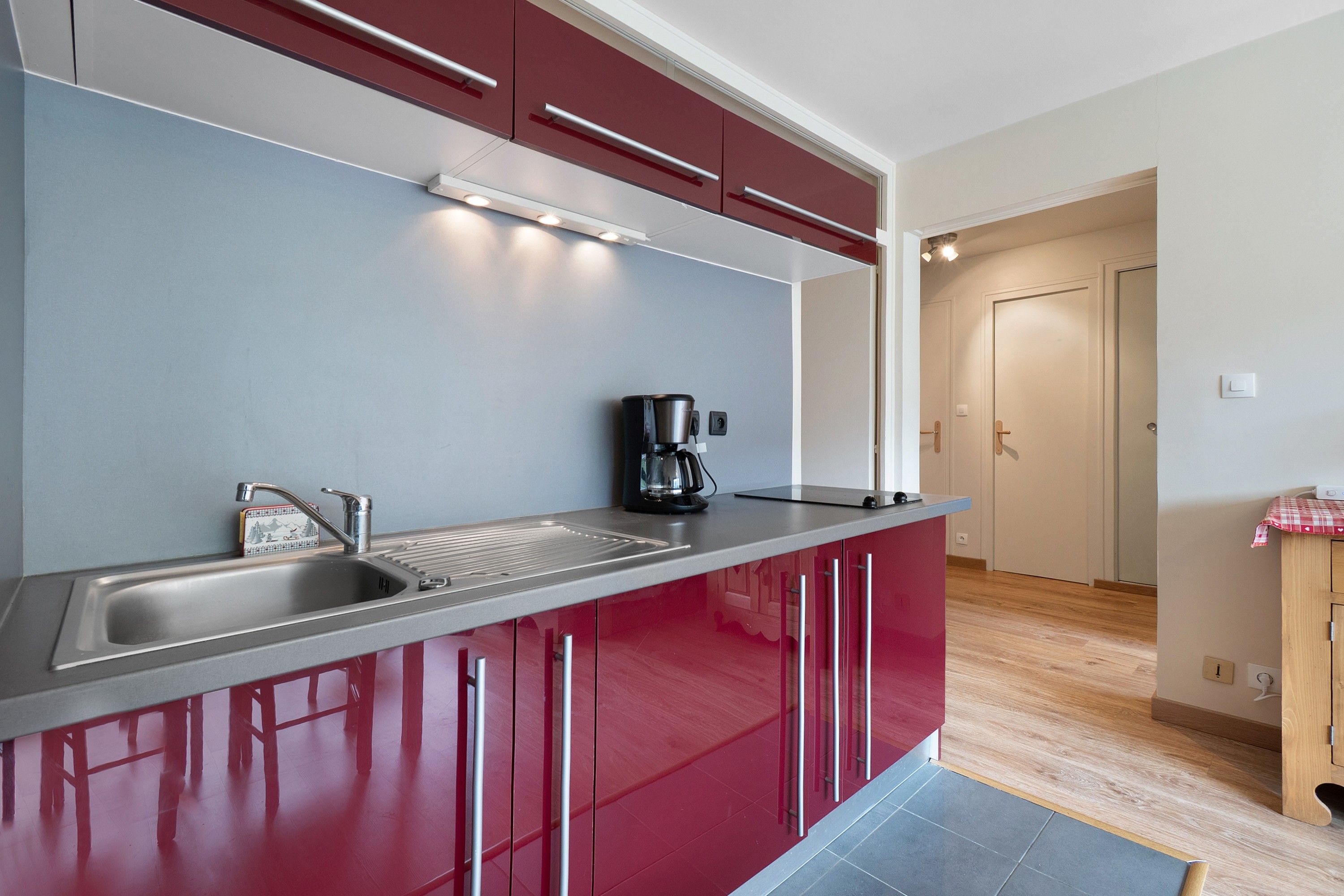 Una cocina moderna con electrodomésticos de acero inoxidable, cafetera y pileta.