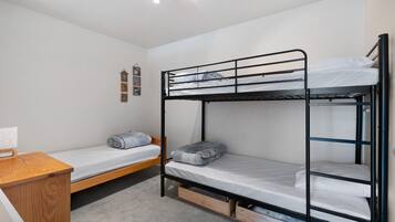 Une chambre avec un lit superposé, un bureau et une horloge au mur.