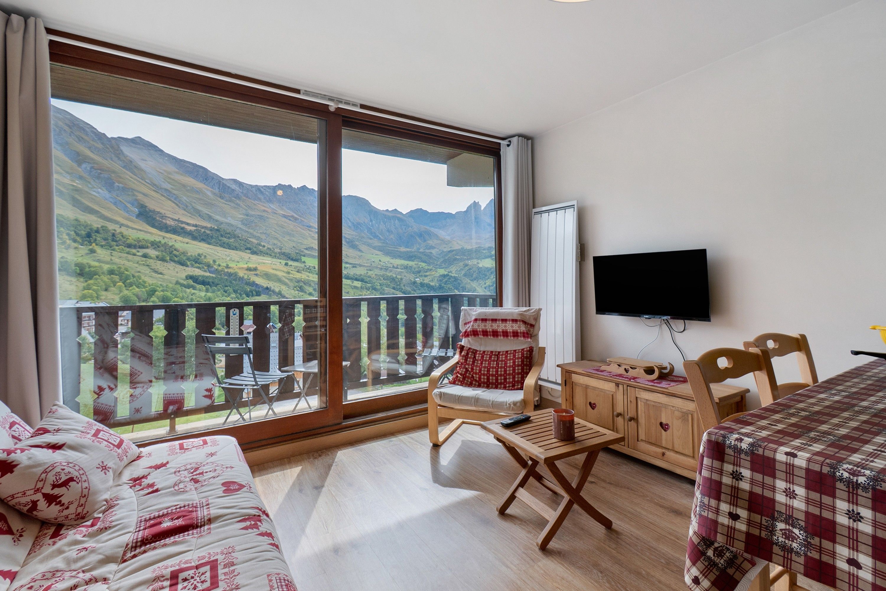 Une chambre dotée d’une grande fenêtre donnant sur les montagnes, avec un lit, une chaise, une petite table et un téléviseur.